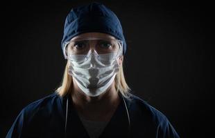 trabajadora médica con mascarilla protectora y equipo contra fondo oscuro foto