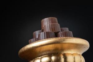 Stack of Fine Chocolates On Golden Pillar Dish With Dark Background photo