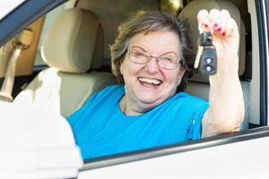 Happy Senior Woman Sitting In New Car Holding The Keys photo