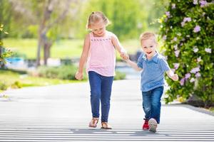 hermana joven y hermano tomados de la mano y caminando en el parque foto