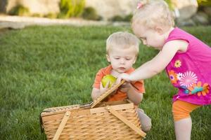 hermano y hermana niños pequeños jugando con manzana y cesta de picnic foto