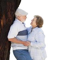 Happy Senior Couple Leaning Against Tree on White photo