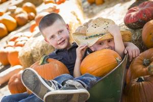 dos niños pequeños jugando en la carretilla en el huerto de calabazas foto