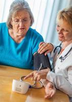 Senior Adult Woman Learning From Female Doctor to Use Blood Pressure Machine photo