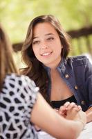 Two Mixed Race Girlfriends Having A Conversation At An Outoor Patio Table photo