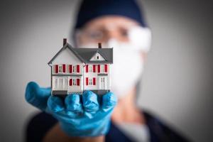 Female Doctor or Nurse Wearing Surgical Gloves Holding Model Home photo