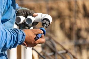 Plumber Applying Pipe Cleaner, Primer and Glue to PVC Pipe At Construction Site photo