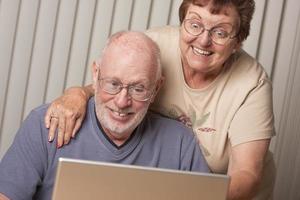 sonriente pareja de adultos mayores divirtiéndose en la computadora foto