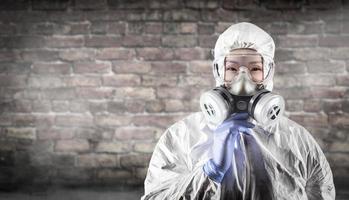 Chinese Woman Wearing Hazmat Suit, Protective Gas Mask and Goggles Against Brick Wall photo