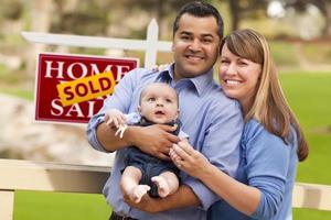 pareja de raza mixta, bebé, signo de bienes raíces vendidos foto