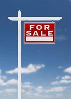 frente a la derecha en venta signo de bienes raíces en un cielo azul con nubes. foto