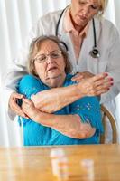 Female Doctor Helping Senior Adult Woman With Arm Exercises photo