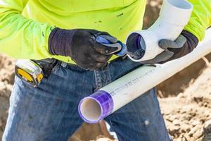 fontanero aplicando limpiador de tuberías, imprimación y pegamento a la tubería de pvc en el sitio de construcción foto