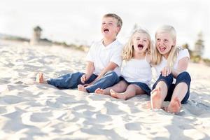 lindos hermanos niños sentados en la playa foto