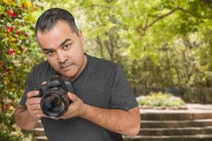 joven fotógrafo hispano con cámara dslr al aire libre foto