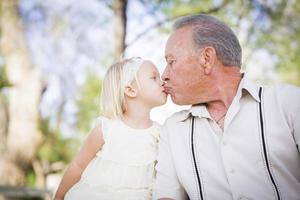 abuelo y nieta besándose en el parque foto