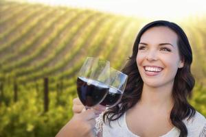 mujer joven disfrutando de una copa de vino en un viñedo con amigos foto