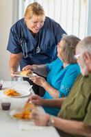 doctora o enfermera que sirve sándwiches para parejas de adultos mayores en la mesa foto