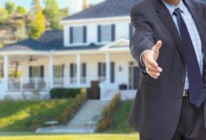 Male Agent Reaching for Hand Shake in Front of Beautiful New House photo