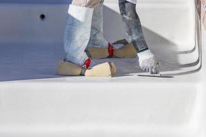 trabajador usando esponjas en los zapatos alisando el yeso húmedo de la piscina con una paleta foto