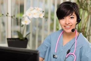 Attractive Multi-ethnic Woman Wearing Headset, Scrubs and Stethoscope photo