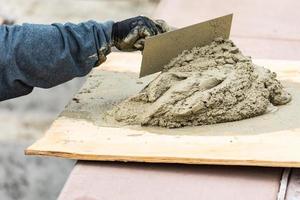 Tile Worker Mixing Wet Cement On Board At Pool Construction Site photo