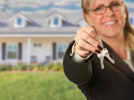 Real Estate Agent Handing Over New House Keys with House Behind photo