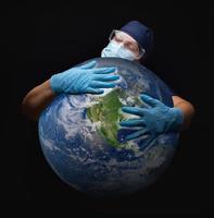 enfermera o médico con mascarilla y guantes quirúrgicos abrazando el planeta tierra foto