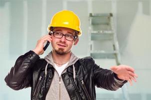 Contractor in Hard Hat on Cell Phone In Unfinished House photo