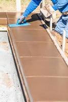 Construction Worker Using Trowel On Wet Cement Forming Coping Around New Pool photo