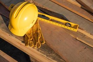 resumen de la construcción de cascos, guantes y nivel descansando sobre tablones de madera