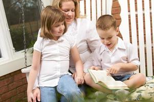 Young Boy Reads to His Mother and Sister photo