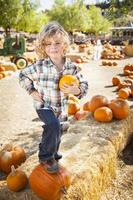 niño pequeño parado en un rancho rústico en el huerto de calabazas. foto