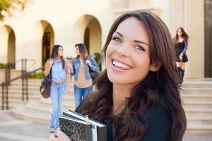 niña sonriente de raza mixta con libros caminando en el campus foto