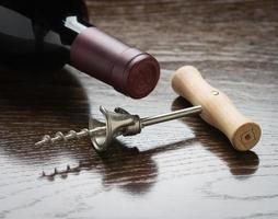 Abstract Wine Bottle and Corkscrew Laying on a Reflective Wood Surface. photo