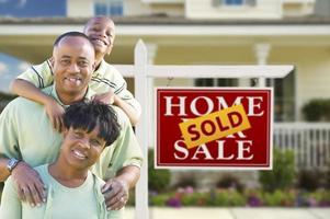 African American Family In Front of Sale Sign and House photo