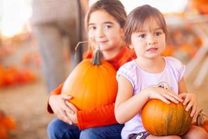 Adorable Little Girls Holding Pumpkins At A Pumpkin Patch photo