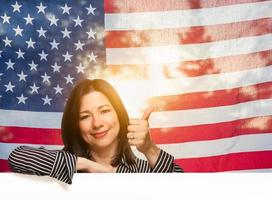 mujer hispana con los pulgares hacia arriba frente a la bandera americana foto