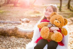 Cute Young Mixed Race Girl Hugging Teddy Bear Outdoors photo