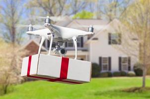 Unmanned Aircraft System UAV Quadcopter Drone Delivering Box With Red Ribbon To Home photo