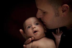 padre joven sosteniendo a su bebé recién nacido de raza mixta foto