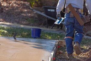 Construction Worker With Trowel Tools Near Wet Deck Cement photo