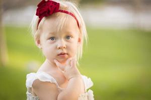 Adorable Little Girl Wearing White Dress In A Grass Field photo