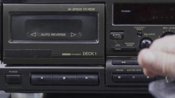 een menselijk hand- zet een cassette Aan de oubollig cassette speler en persen de Speel knop video