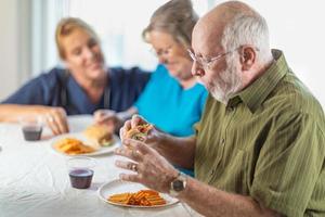 doctora o enfermera que sirve sándwiches para parejas de adultos mayores en la mesa foto