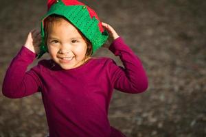 Cute Mixed Race Young Baby Girl Having Fun Wearing Christmas Hat Outdoors photo