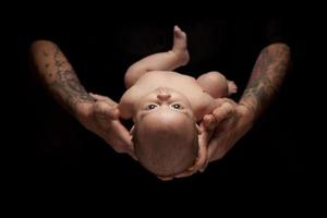 Hands of Father and Mother Hold Newborn Baby on Black photo