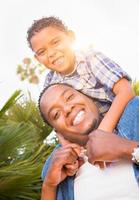 Mixed Race Son and African American Father Playing Piggyback Outdoors Together. photo