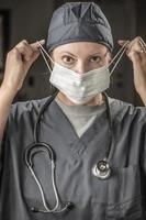 Female Doctor or Nurse with Stethoscope Putting On Protective Face Mask photo