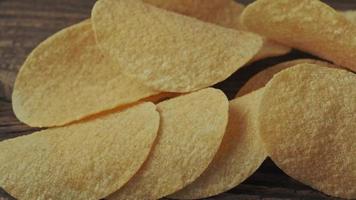 Potato chips on a wooden background. Salty crisps scattered on a table. video